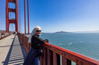 © Tetra Images - Portrait of smiling woman standing on Golden Gate Bridge on sunny day