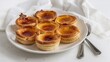 © Thefoodvids - Portuguese Pastel de Nata Custard Tarts Arranged on White Background