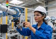 © Vasiliy - Female engineer adjusting a robotic arm in a modern factory. Young woman technician working on industrial automation equipment