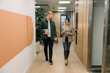 © Franci Leoncio - Business professionals walking and talking in office hallway