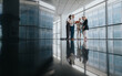 © qunica.com - Diverse coworkers stand in a modern office corridor, sharing documents and ideas. A reflective, sleek floor adds drama as they collaborate and connect.