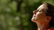 © PaulShlykov - Mindful woman enjoying nature while taking a deep breath in a lush green environment during a sunny day