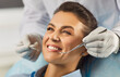 © Studio Romantic - Close up portrait of smiling woman sitting in dental chair during checkup while dentist in gloves holding dental tools, ensuring proper oral care during regular medical check up in dentistry clinic.