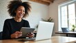 © Vadym - Young Latina woman laughs holding tablet while working on laptop in modern office. Freelancer communicates with friends online using tech gadgets, smiling brightly at screen, happy lifestyle.