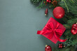 © RooM The Agency - Overhead view of a wrapped Christmas gift box, festive Christmas baubles and ornaments with fir branches on a green background