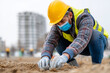 © Anastasiia Havelia - Worker in protective gear checking ground level with tools on a construction site, with copy space