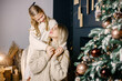 © prostooleh - Young mother and little girl sitting christmas tree at home and hugging