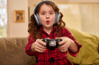 © SuperStock - Young girl wearing headphones plays video games with controller on living room couch