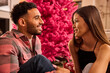 © SuperStock - Young couple enjoying a romantic conversation together in front of vibrant pink floral backdrop