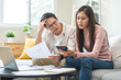 © KMPZZZ - Stressed financial owe asian young couple love sitting suffer, stressed and confused by calculate expense from credit card bill, no money to pay, mortgage or loan. Debt, bankrupt or bankruptcy people.