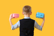 © Pixel-Shot - Cute little schoolboy with lunchboxes on yellow background, back view