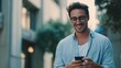 © M Alfan Setyawan - Young Smiling Man Wearing Glasses Using Smartphone Outdoors in City Environment