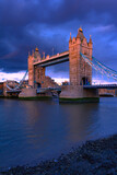 Tower Bridge, the iconic landmark of London spanning the River Thames, captured in a romantic moment. The elegant structure, illuminated against the water, evokes a sense of charm and timeless beauty.