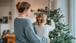 © t.sableaux - Parent and child decorating a Christmas tree in a cozy living room, warm glow from lights creating a festive atmosphere for the holiday season