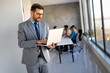 © NDABCREATIVITY - Young businessman using laptop computer in office. Manager thinks about successful financial ideas.