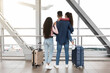 © Prostock-studio - Family of three is at the airport, looking out the large window at an airplane taking off. They are standing near their suitcases, excited for their trip.