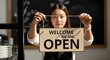 © Helen - Woman holding an open sign, ready to welcome customers to the business
