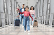© Prostock-studio - A joyful girl walks through the airport terminal, holding her teddy bear. Her parents follow closely, each with a suitcase, ready for their journey together.
