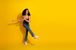 © deagreez - Young woman dancing against a vibrant yellow background in casual chic outfit smiling with energy and style for lifestyle fashion stock