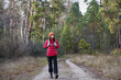 © Akhtiamova - A young woman with a backpack is walking along a forest path. Hiking in the forest in autumn. Pine trees surround her, creating a serene atmosphere in the fresh air.