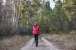 © Akhtiamova - A young woman with a backpack is walking along a forest path. Hiking in the forest in autumn. Pine trees surround her, creating a serene atmosphere in the fresh air.