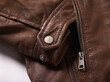 © Connect Images - Close-up of a brown leather jacket with a metal zipper and button detail.