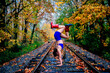 © Connect Images - Woman in blue athletic wear does a handstand on railroad tracks surrounded by autumn trees. WA, USA