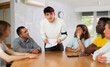 © JackF - Focused young guy student holding papers ad discussing assignments or projects with interested male group of various ages and nationalities gathered around table in classroom..