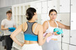 © JackF - Two young women in sportswear talking near lockers in locker room..