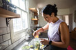 © Marko Geber - Young adult woman preparing healthy smoothie in home kitchen, focused
