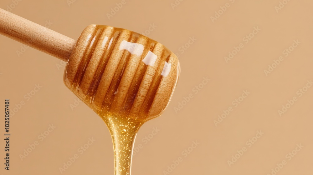 Golden honey flows from a wooden dipper, showcasing its thick texture. The dipper holds the sticky sweetness, complementing the soft beige background that highlights its rich color.