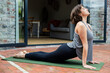 © Wavebreak Media - Woman in athletic wear practicing yoga backbend on mat on patio outside sliding doors, copy space