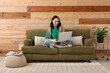 © Pixel-Shot - Pretty young woman using modern laptop on green couch at home