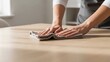 © warnadi - Close-up shot of a person's hands wiping down a wooden table with a cloth, symbolizing cleanliness and household chores