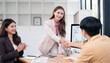© NAMPIX - Smiling Asian businesswoman shaking hands with a male colleague across the table to seal a deal or welcome a partner during an office meeting.