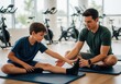 © Meow Creations - Male coach assisting a preteen boy with stretching exercises in a gym