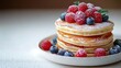 © video - Stack of fluffy pancakes on a white plate topped with fresh raspberries, blueberries and a dusting of powdered sugar with a mint leaf, inviting and indulgent breakfast scene