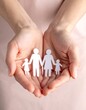 © candra - Two hands cupping a paper family cutout, warm and safe