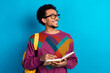 © deagreez - Smiling young man holding a notebook on blue background showcasing vibrant style and casual fashion with joy