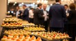 © graphic35 - Catering service offering a variety of gourmet canaps and appetizers displayed on a buffet table during a corporate event or reception with blurred business people in background