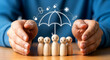 © Ms - Human hands protecting a group of wooden figures under an umbrella with healthcare icons, representing family health insurance and security