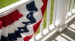 © antuanetto - American flag bunting draped over railing on sunny day for Independence Day