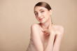 © kitthanes  - A beautiful young woman with clean, fresh skin against a beige background. Skincare, facial treatment, cosmetology, beauty, and spa. An elegant portrait of an woman.