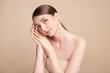 © kitthanes  - A beautiful young woman with clean, fresh skin against a beige background. Skincare, facial treatment, cosmetology, beauty, and spa. An elegant portrait of an woman.