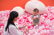 © leungchopan - Happy mum enjoying playful moment with son in pink ball pit
