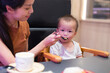 © leungchopan - Young mother feeding baby inside sushi shop