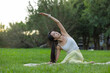 © leungchopan - Woman doing stretching exercises outdoors in park grass
