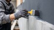 © TensorSpark - Worker applying concrete coating with sealant to basement wall for waterproofing and surface protection.