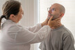 © kittyfly - woman doctor or nurse examines neck and lymph nodes male patient checking thyroid gland medical examination and diagnosis, physical exam procedure, health care environment, medical professional role