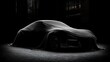 © irawan - Sleek shape of a covered automobile suggested by dramatic dark lighting on a paved surface
